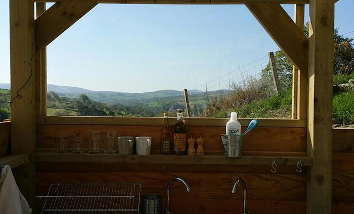The sink and drainer in the outdoor kitchen with a stunning blue sky and rolling green hills of North Wales.